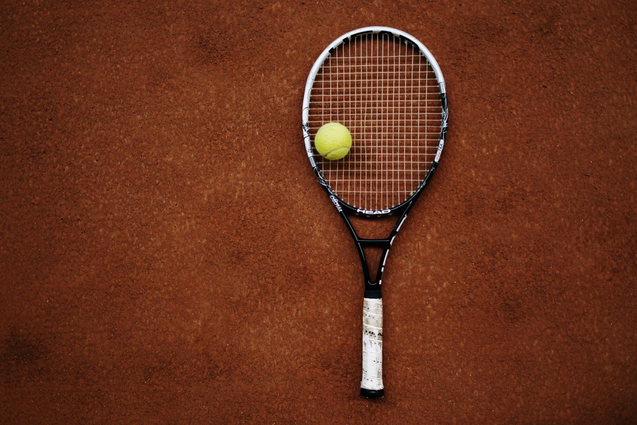 Services Tennis racket and ball on clay court, perfect for sports imagery.